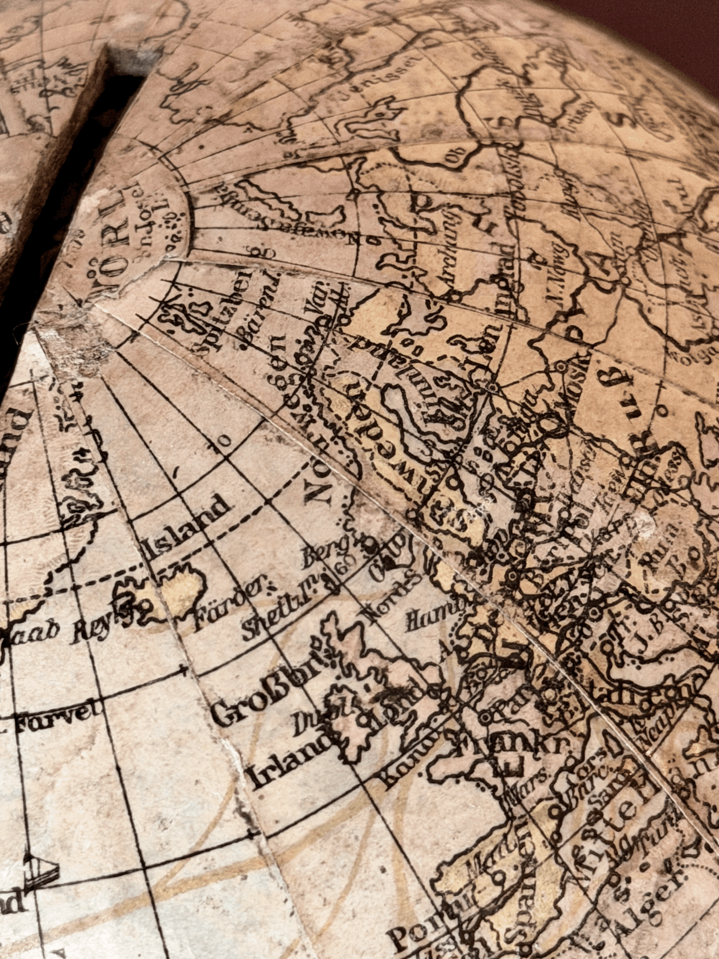 Rare 1920s antique German paper-mâché world globe bank by Paul Räth Leipzig, hand-wrapped in paper map gores showing an amber sepia patina, craquelure varnish, and a narrow coin slot cut directly into the North Pole.