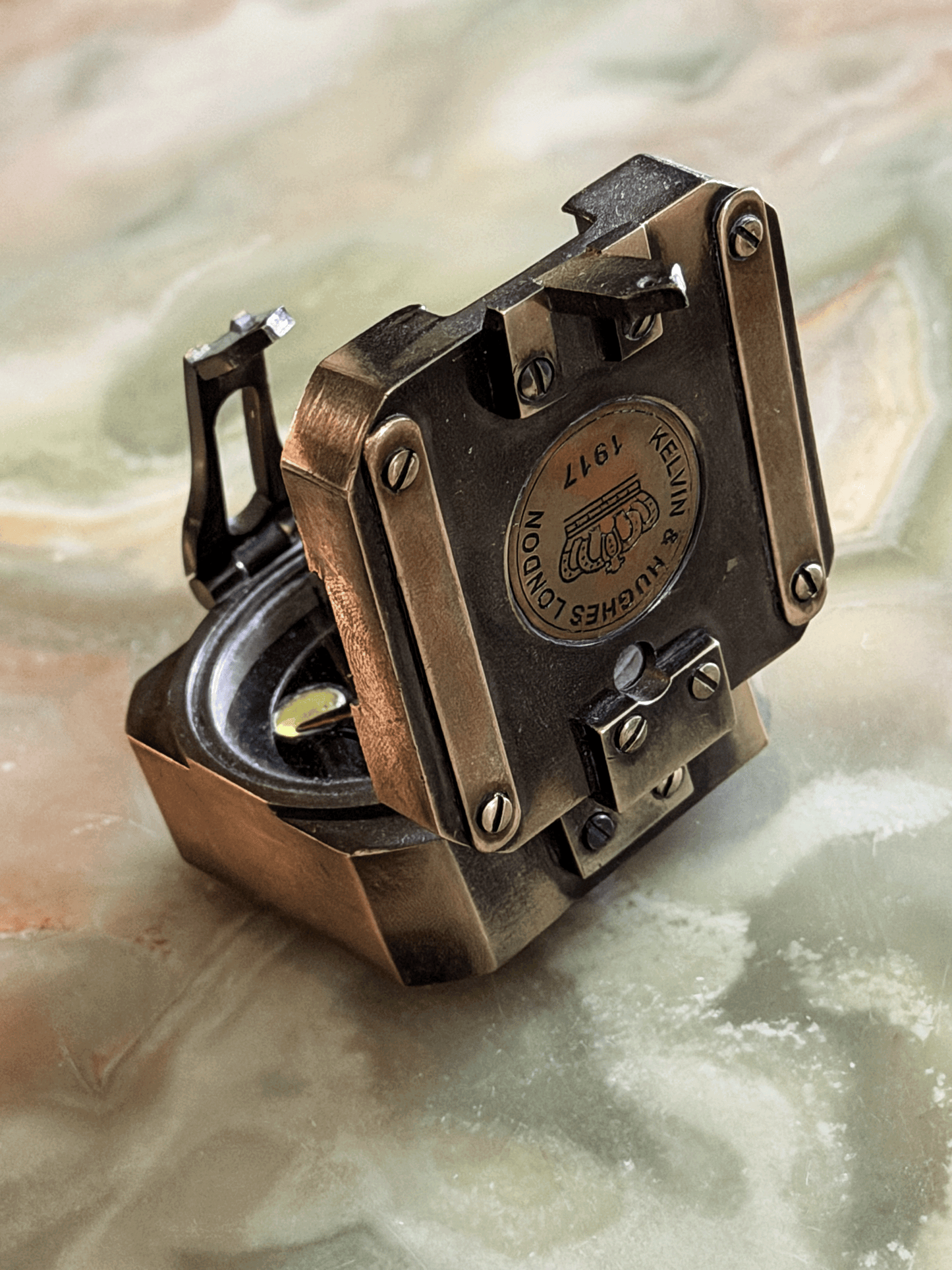 antiqued reproduction brass pocket transit, featuring an inlaid circular brass medallion stamped with a British crown emblem and the historical fantasy hallmark Kelvin and Hughes London 1917.