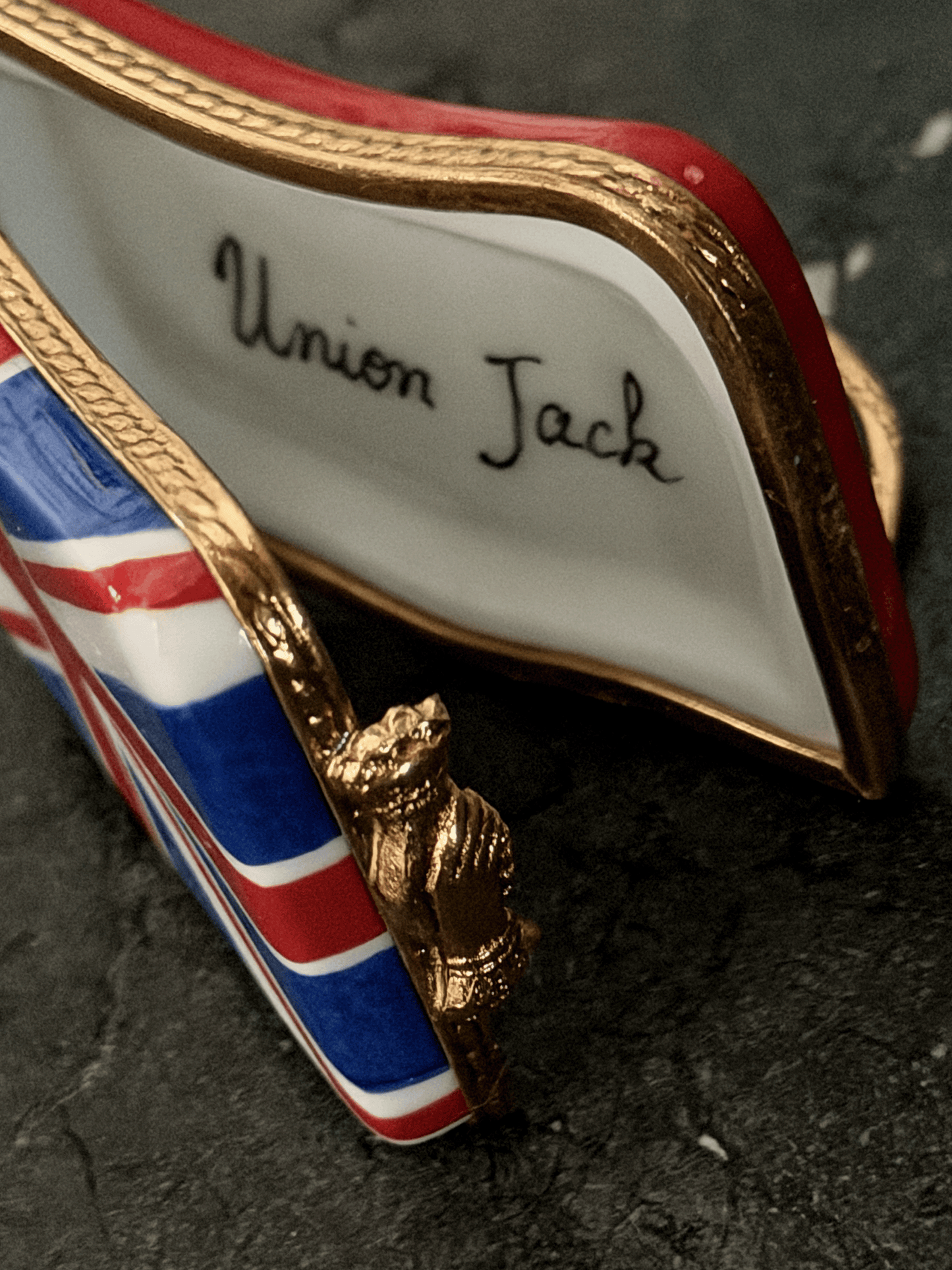 Hand-painted French porcelain Limoges box shaped like a wavy vintage kiss lock coin purse decorated with the British Union Jack flag, featuring an ornate brass frame and a three-dimensional miniature Royal Guard metal clasp latch.