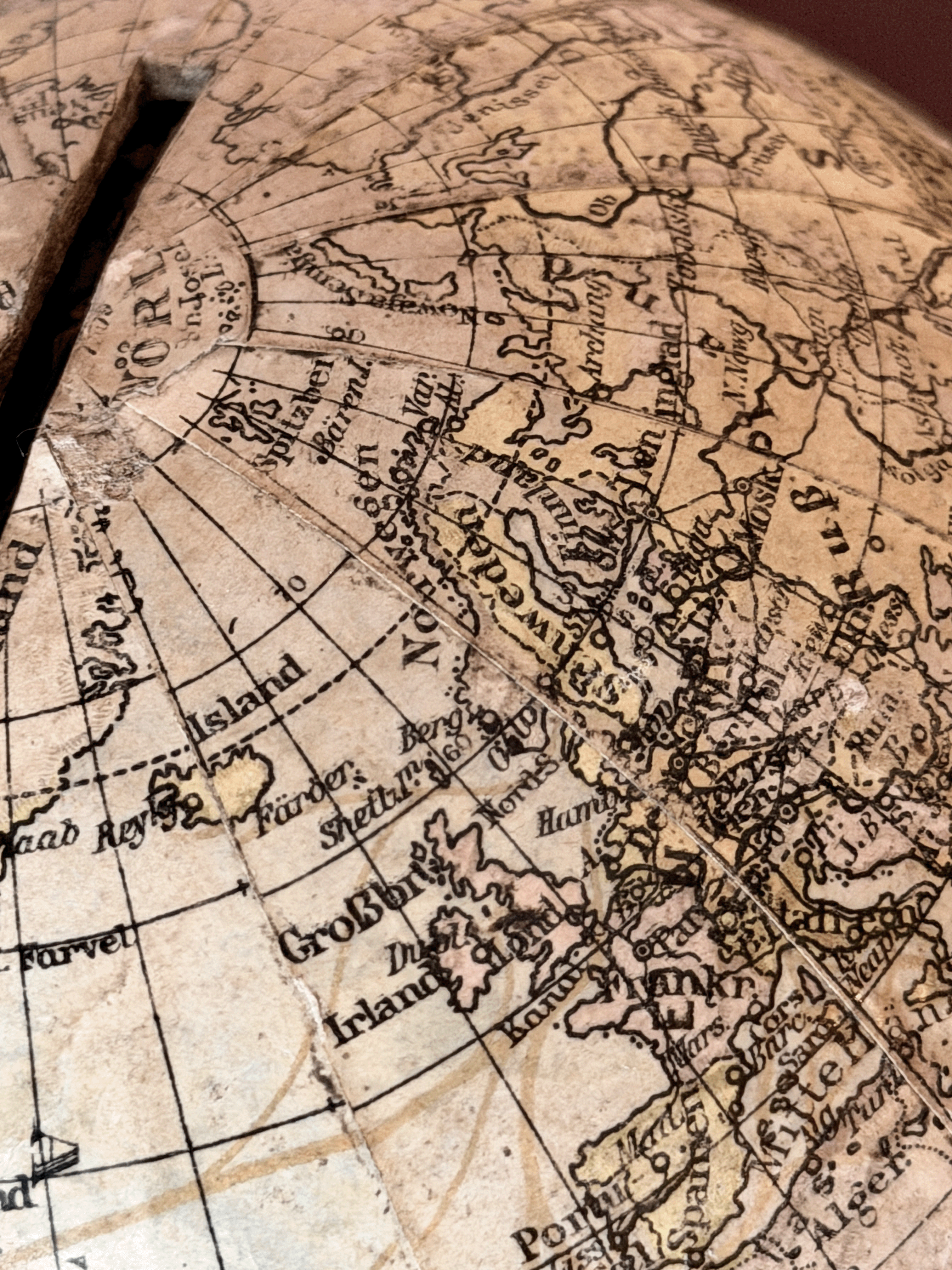 Rare 1920s antique German paper-mâché world globe bank by Paul Räth Leipzig, hand-wrapped in paper map gores showing an amber sepia patina, craquelure varnish, and a narrow coin slot cut directly into the North Pole.