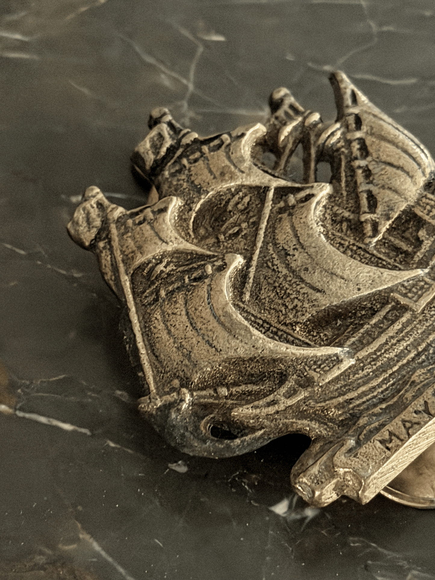 Close-up of vintage solid brass door knocker cast in the shape of the historical Mayflower pilgrim sailing ship, featuring a detailed multi-masted galleon hull with a dark aged patina in the recessed engraving.