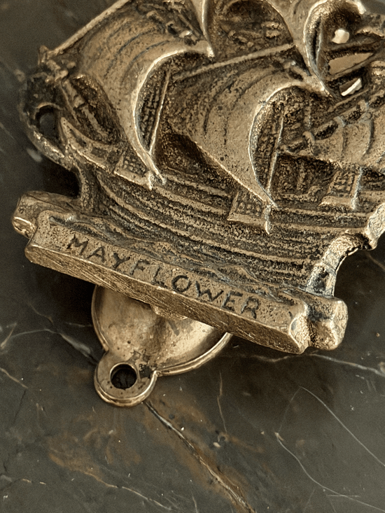 Vintage mid-century solid brass door knocker cast in the shape of the historical Mayflower pilgrim sailing ship, featuring a detailed multi-masted galleon hull with a dark aged patina in the recessed engraving.