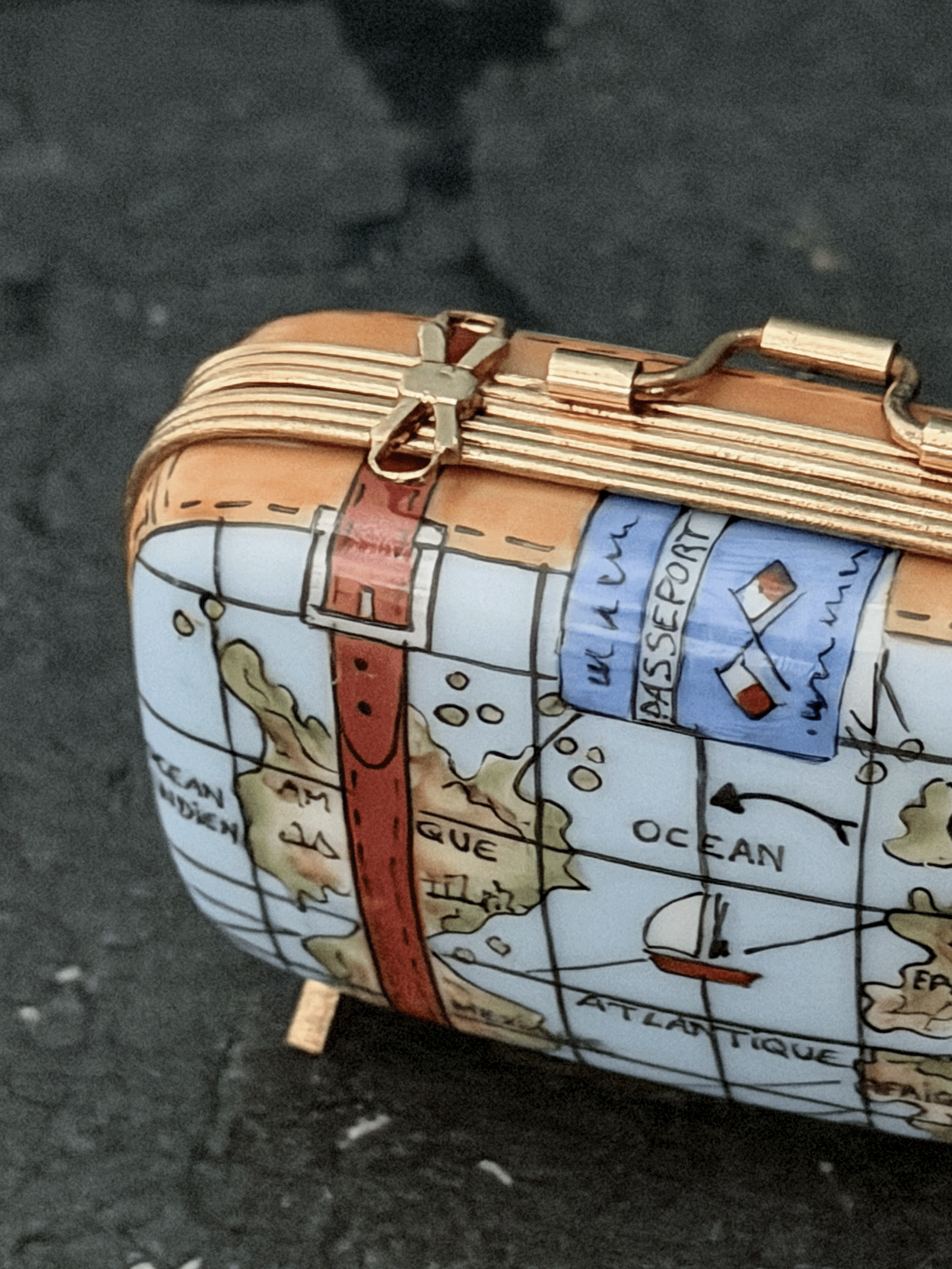 Close-up of a Rochard porcelain map suitcase trinket box, emphasizing hand-painted ocean geography reading Ocean Atlantique and Amerique alongside an illustrated historic red-sailed galleon ship.