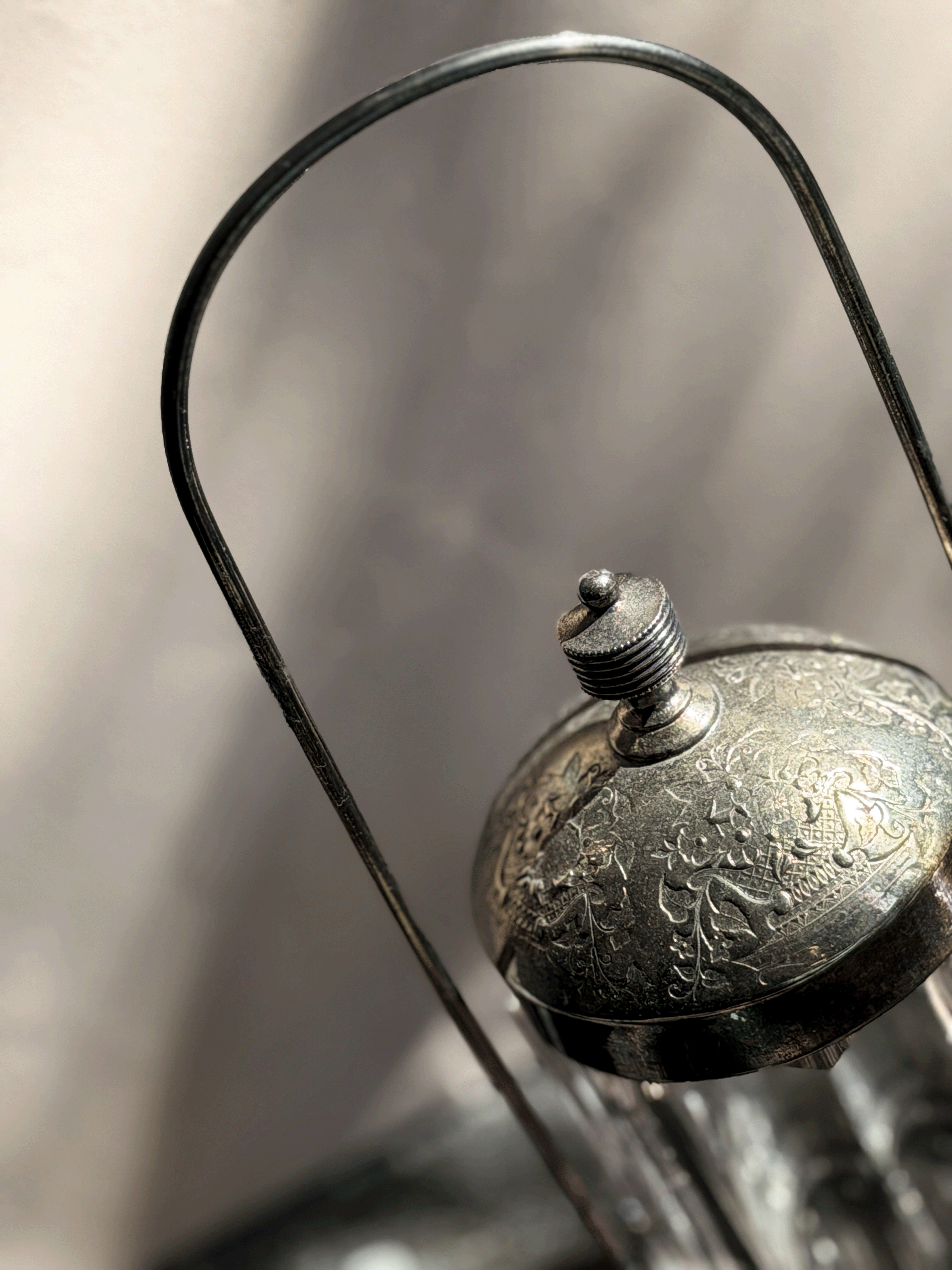 Antique Victorian silver-plated pickle castor featuring a clear vertical-paneled glass jar nested inside a tall, arched lantern-style metal frame with a shadow backdrop.
