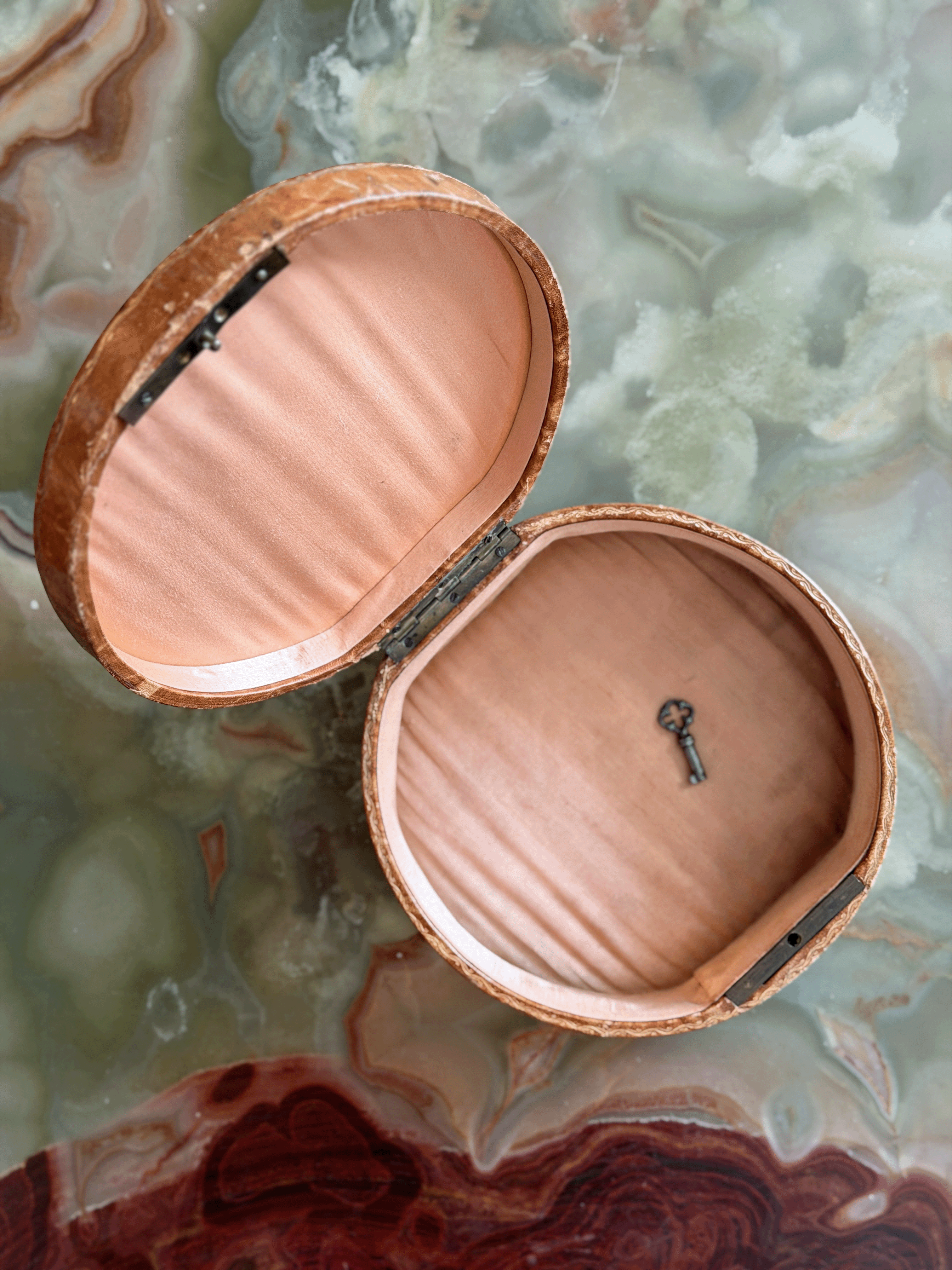 Antique French Grand Tour leather vanity box from the early 20th century, opened to reveal a blush-pink ruched silk faille interior and original steel barrel key.