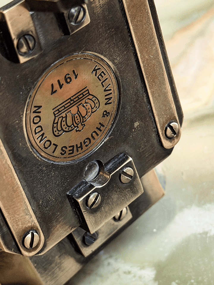 antiqued reproduction brass pocket transit, featuring an inlaid circular brass medallion stamped with a British crown emblem and the historical fantasy hallmark Kelvin and Hughes London 1917.