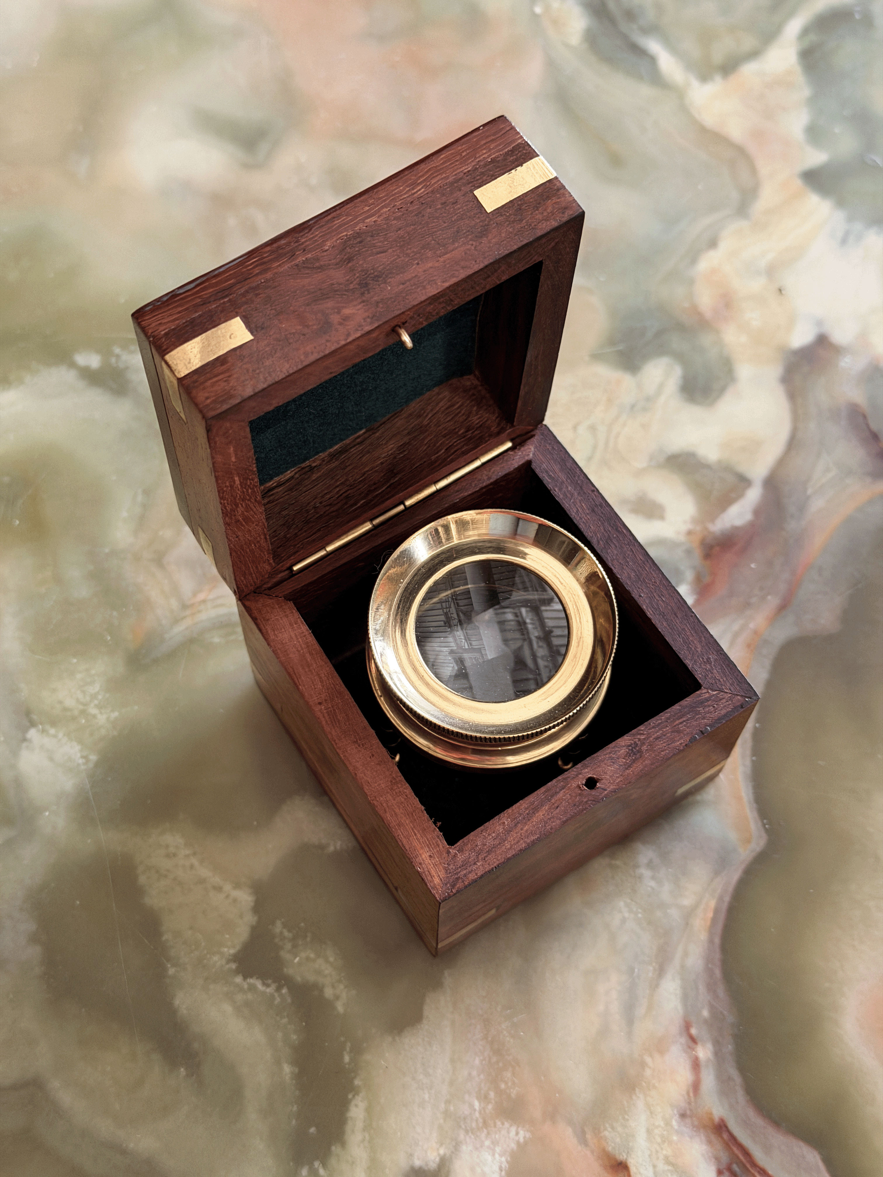 Mid-century executive desk accessory set showing a solid brass adjustable tripod map reader magnifying glass standing next to its matching polished rosewood storage box with a brass diamond inlay lid.