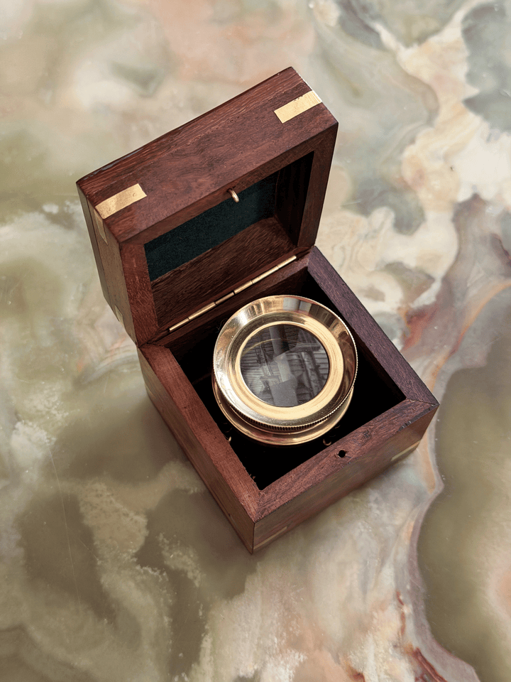 Mid-century executive desk accessory set showing a solid brass adjustable tripod map reader magnifying glass standing next to its matching polished rosewood storage box with a brass diamond inlay lid.