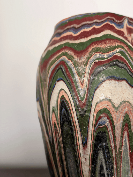 Close-up of ozark pottery vase with a marbled, wavy pattern in green, red, cream, black, and blue drip glaze.