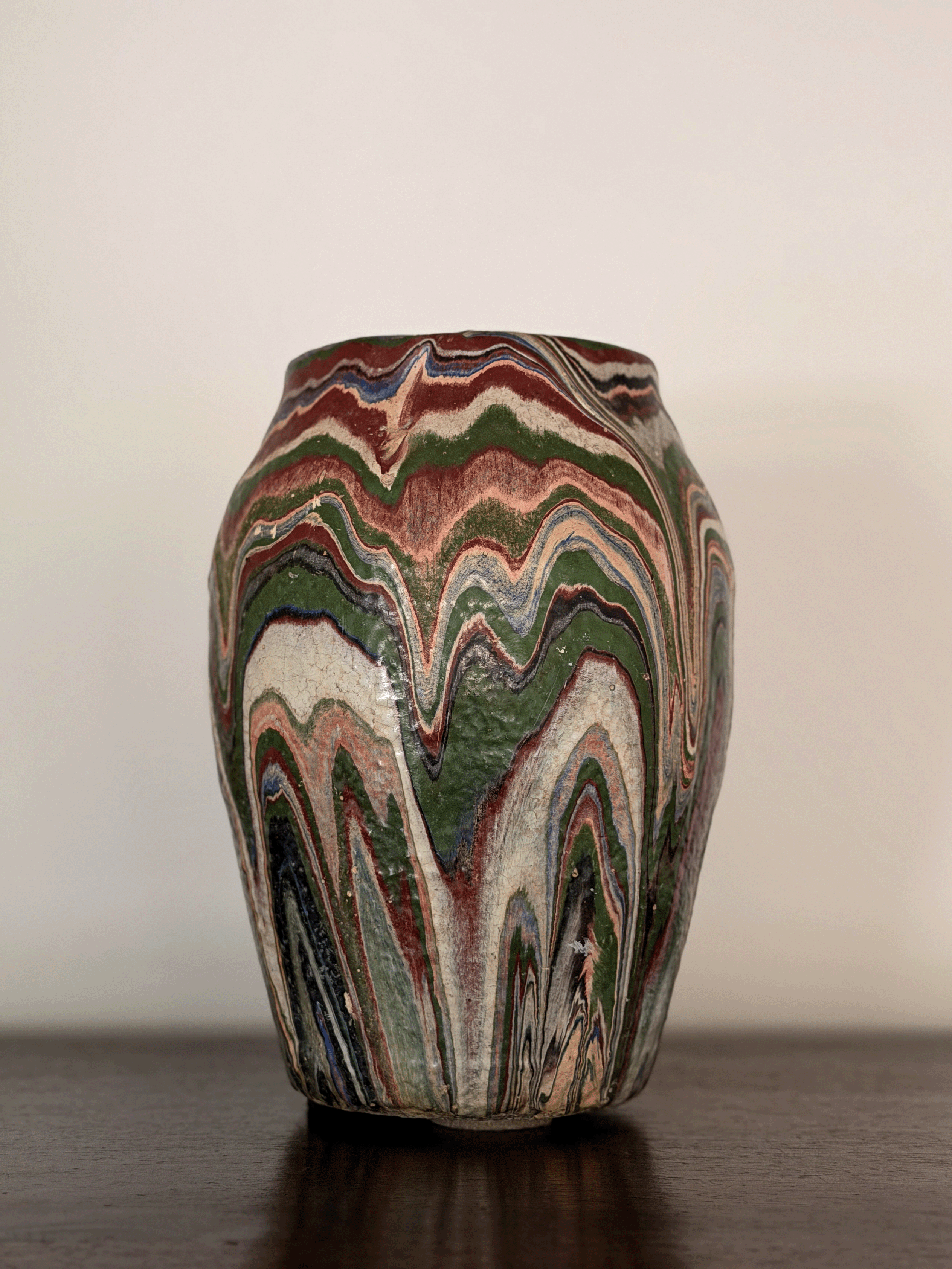 Imposing front-view photo of a large 10-inch tall antique Ozark tourist pottery vase featuring heavy, textured, flame-like wavy swirls of blue, rust, green, and cream paint.