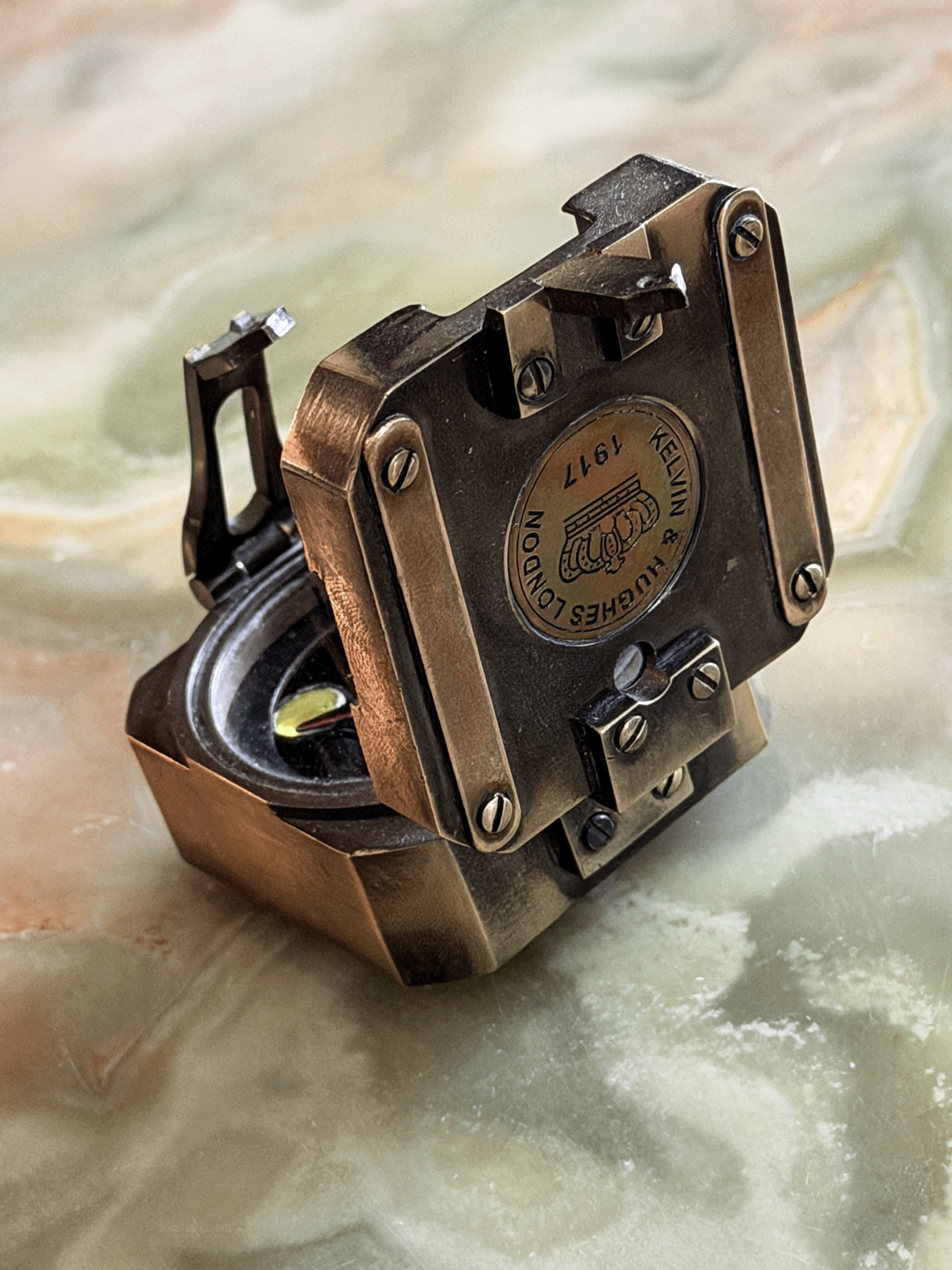 antiqued reproduction brass pocket transit, featuring an inlaid circular brass medallion stamped with a British crown emblem and the historical fantasy hallmark Kelvin and Hughes London 1917.