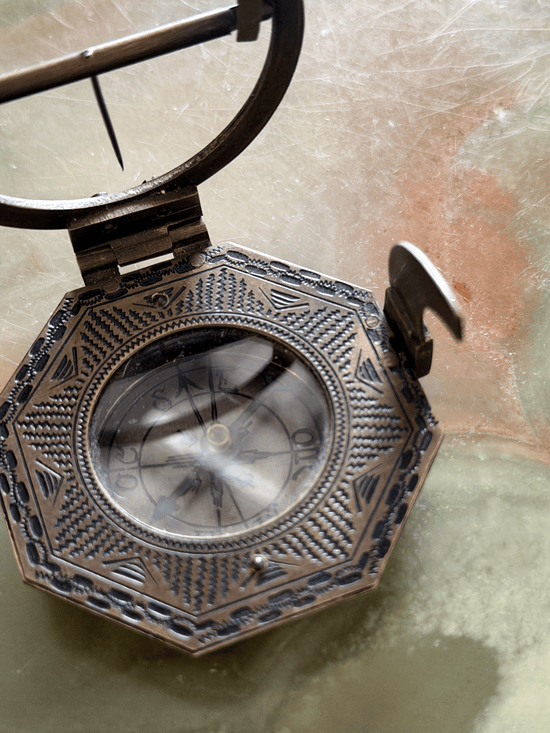 Engraved underside of a reproduction brass pocket sundial, replicating an 18th-century German instrument with an Elev. Pol. latitude table for Augsburg, Paris, Cracau, and Liège alongside the maker signature Schretegger.