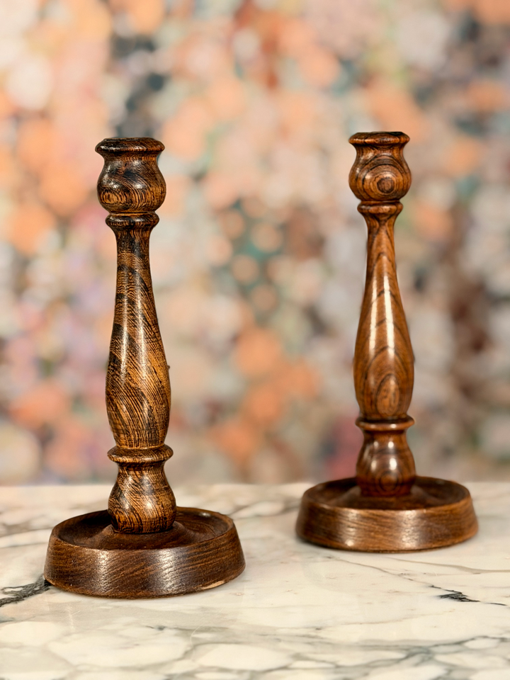 Two wooden candle holders on a marble surface with a blurred abstract background