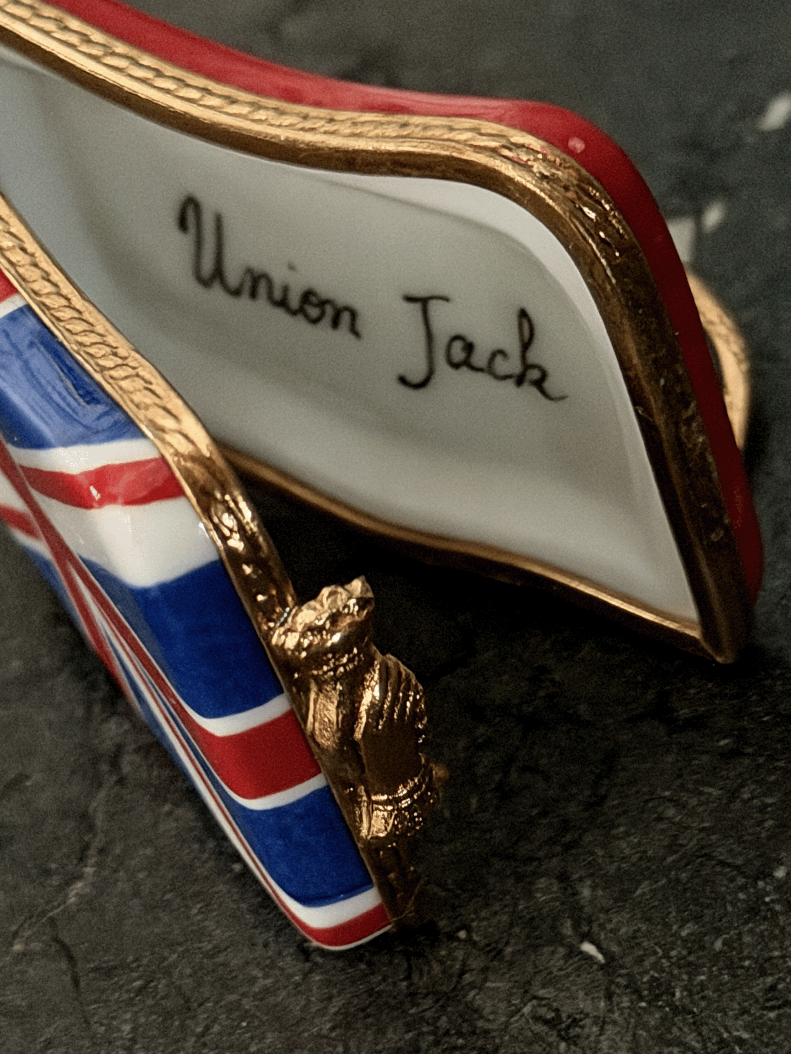 Hand-painted French porcelain Limoges box shaped like a wavy vintage kiss lock coin purse decorated with the British Union Jack flag, featuring an ornate brass frame and a three-dimensional miniature Royal Guard metal clasp latch.