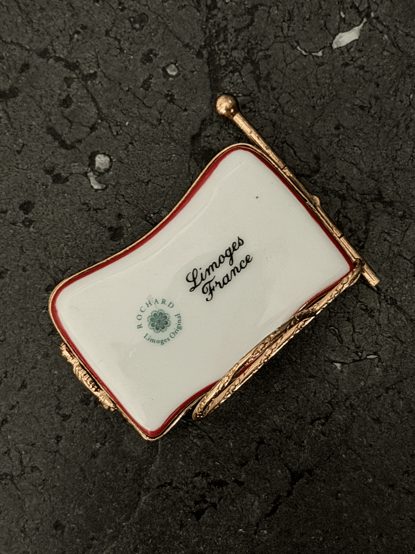Underside base view of a wavy hand-painted Rochard porcelain trinket box, showing a bright white glazed surface stamped with the green circular ROCHARD Limoges Original floral seal and black cursive Limoges France script.