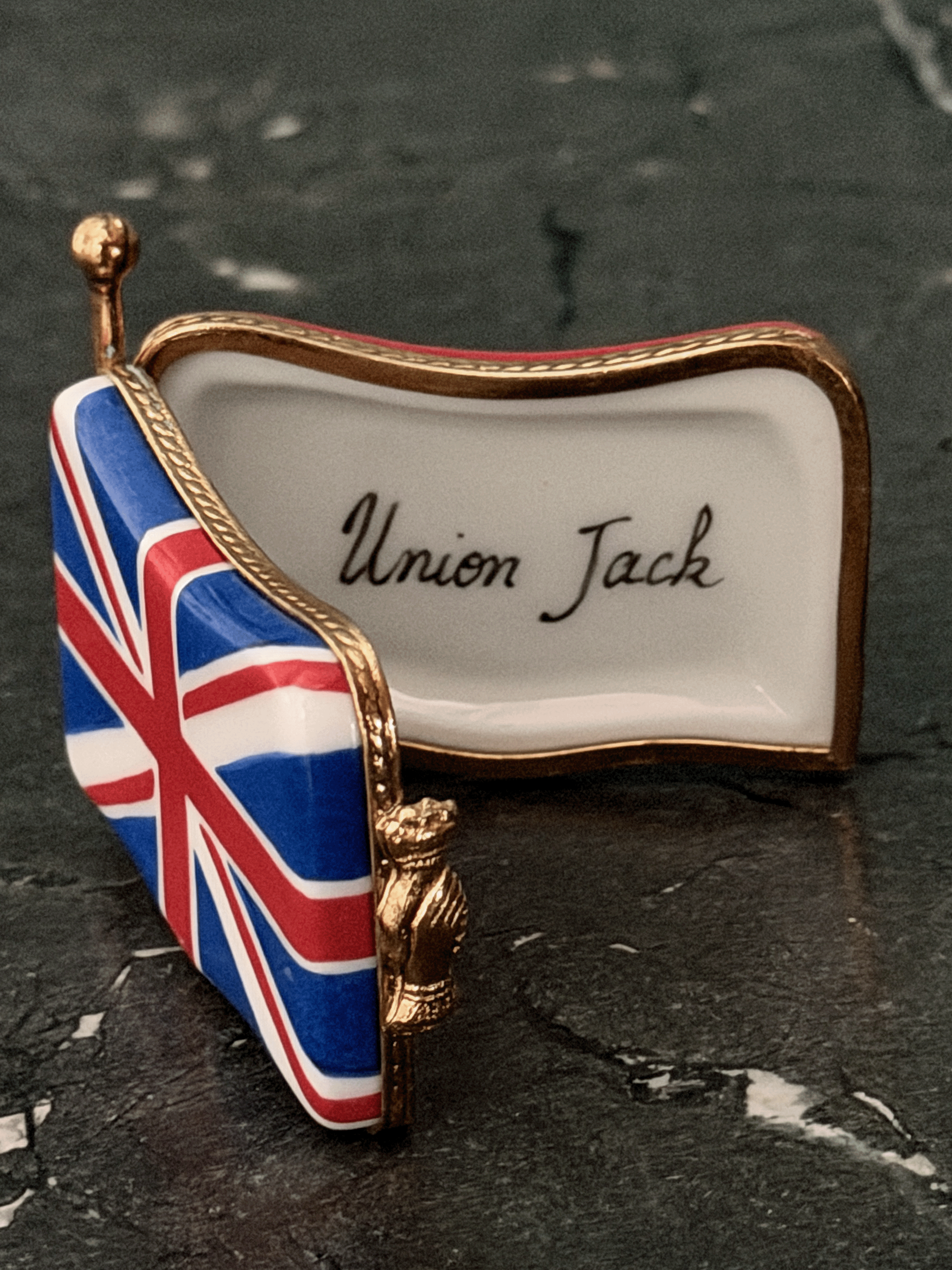 Hand-painted French porcelain Limoges box shaped like a wavy vintage kiss lock coin purse decorated with the British Union Jack flag, featuring an ornate brass frame and a three-dimensional miniature Royal Guard metal clasp latch.