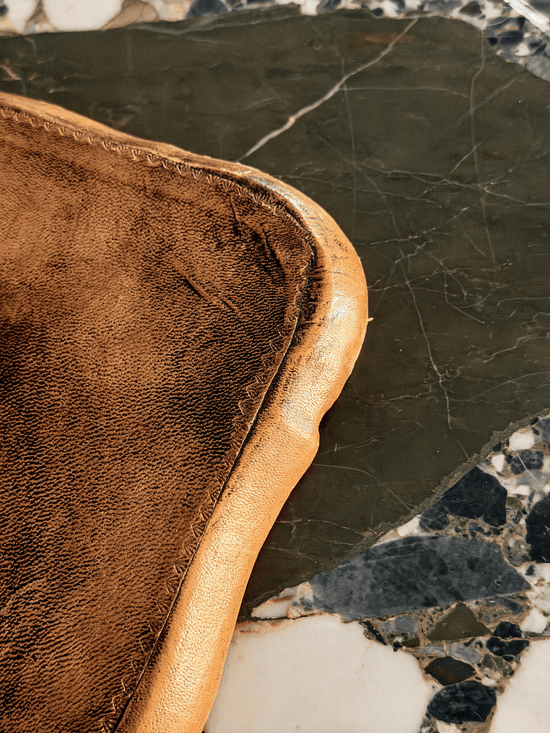 Underside corner of a vintage Italian leather desk tray, highlighting a tight hand-stitched blind border seam securing the pebble-grain leather wrap over a molded papier-mâché structural core.