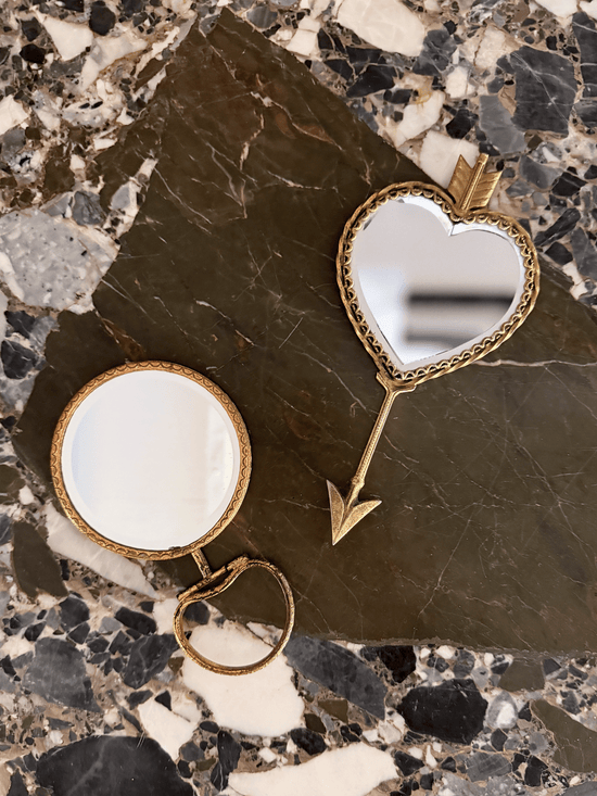 two vintage handheld mirrors, his and hers, with brass frames and intricate detailing