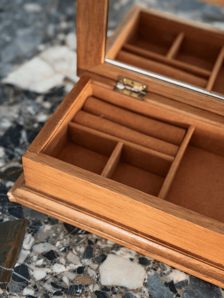 A wooden jewelry organizer box with a hinged lid, open to reveal multiple compartments and a mirror on the inside lid.