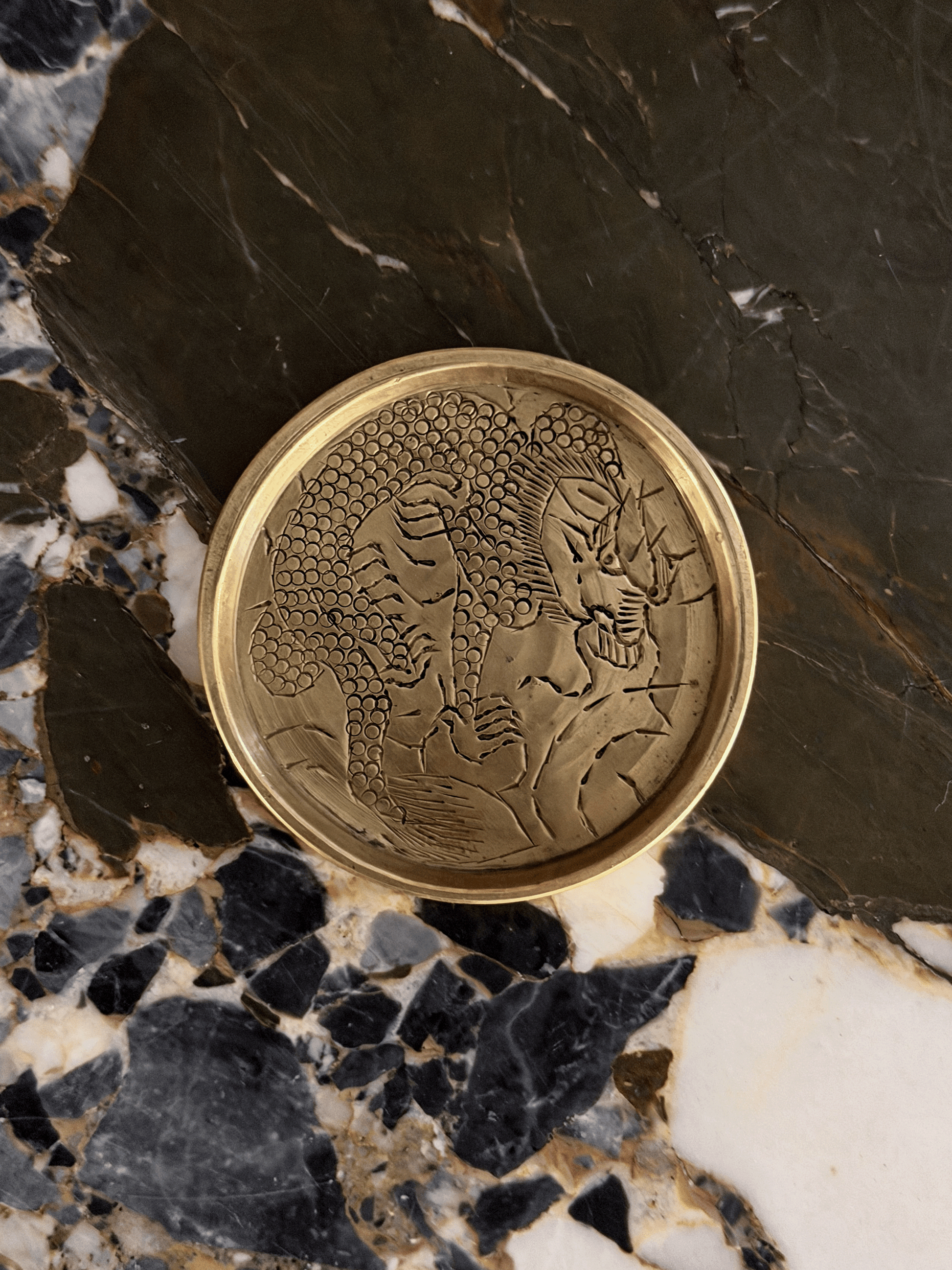 Miniature vintage round brass tray with dragon etching on marble surface