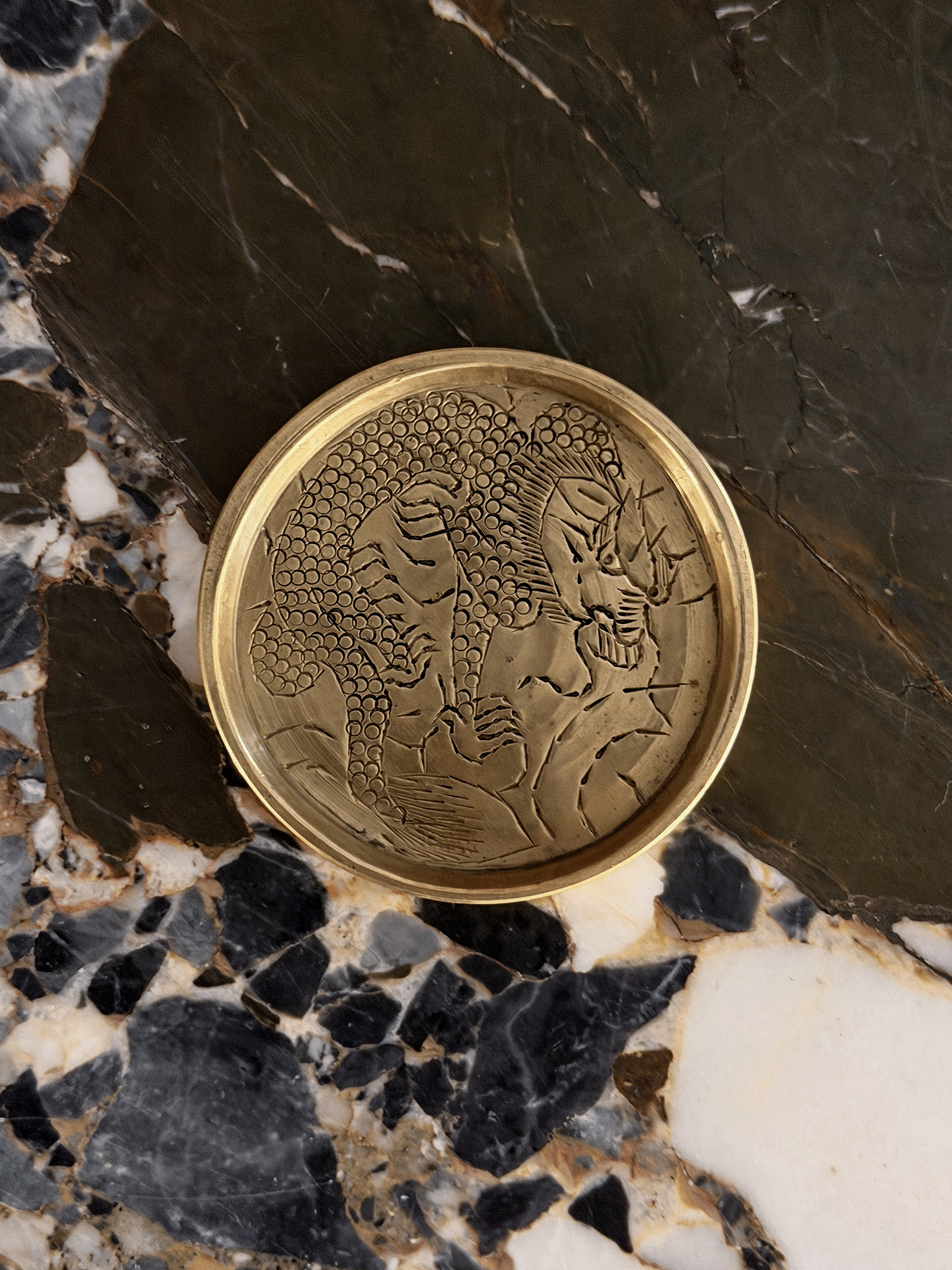 Miniature vintage round brass tray with dragon etching on marble surface
